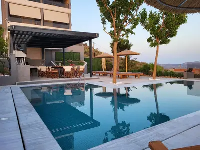 a swimming pool with a table and a house at Stergiou Luxury Apartments με κοινη πισινα in Saronida