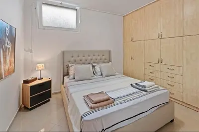 a bedroom with a large bed with a wooden cabinet at Βίλα Λαγονήσι in Kalívia Thorikoú
