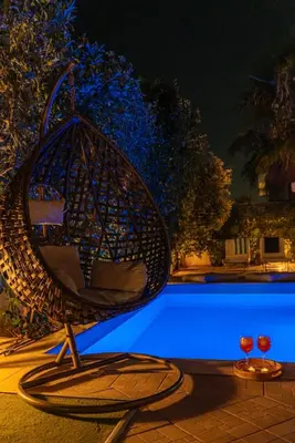 a wicker chair sitting next to a pool at night at Βίλα Λαγονήσι in Kalívia Thorikoú