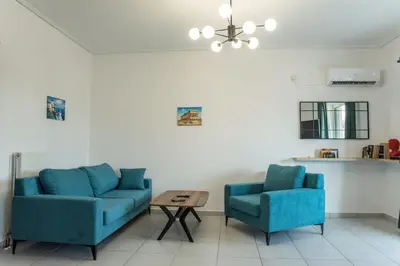 a living room with two blue chairs and a table at Asclepius apartment Athens Airport in Spáta