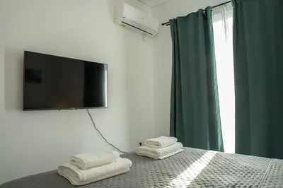 a bedroom with two towels on a bed with a flat screen tv at Asclepius apartment Athens Airport in Spáta