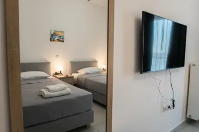a bedroom with two beds and a flat screen tv at Asclepius apartment Athens Airport in Spáta