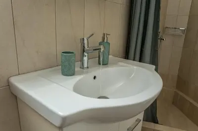 a white sink in a bathroom with a shower at Asclepius apartment Athens Airport in Spáta