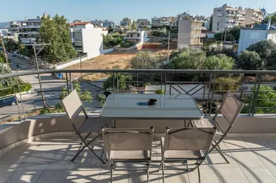 a table and chairs on a balcony with a view at Asclepius apartment Athens Airport in Spáta