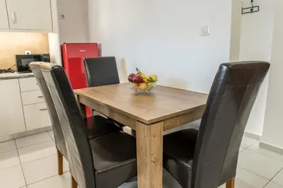 a wooden table with chairs and a bowl of fruit on it at Asclepius apartment Athens Airport in Spáta