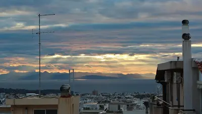 a view of a city with the sunset in the background at Sea & garden view cozy apartment with good privacy in Athens