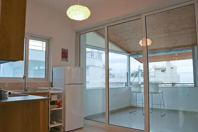 a kitchen with sliding glass doors and a refrigerator at Sea & garden view cozy apartment with good privacy in Athens
