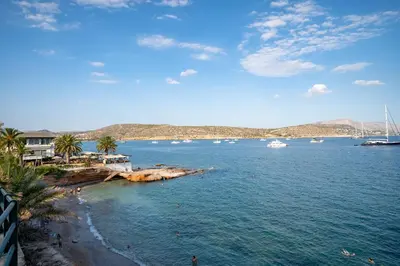 a beach with palm trees and boats in the water at Seaview Balcony in Varkiza by ΜΡS in Vari