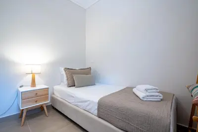 a small bedroom with a bed and a night stand at Seaview Balcony in Varkiza by ΜΡS in Vari