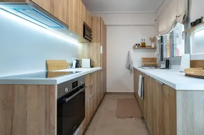 a kitchen with wooden cabinets and a black dishwasher at Seaview Balcony in Varkiza by ΜΡS in Vari