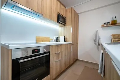 a kitchen with wooden cabinets and a black oven at Seaview Balcony in Varkiza by ΜΡS in Vari