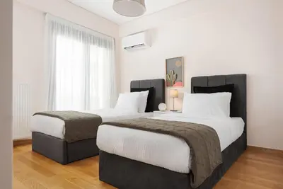 two beds in a hotel room with white walls at Glyfada Golden Stay in Athens