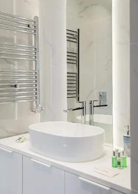 a white bathroom with a sink and a mirror at Glyfada Golden Stay in Athens