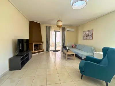 a living room with a blue couch and a tv at Anavyssos Azure in Anavissos
