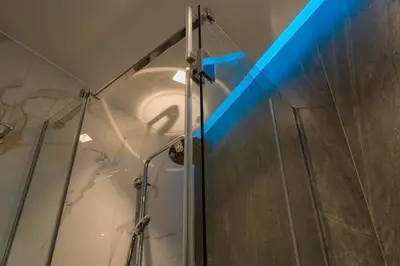 a shower with a blue light in a bathroom at Highway Haven - Halandri in Athens