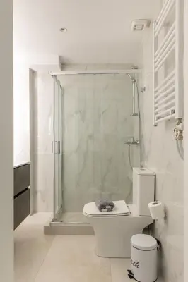 a white bathroom with a shower and a toilet at Andria's Apartment in Athens