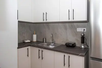 a kitchen with white cabinets and a sink at Ilissos Harmony Apartment in Piraeus