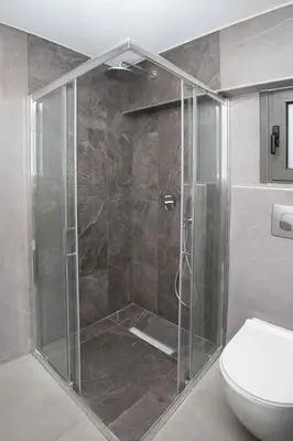 a shower with a glass door next to a toilet at Ilissos Harmony Apartment in Piraeus