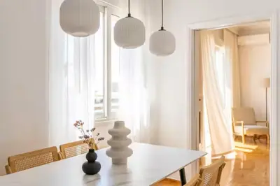 a white dining room with a table and some pendant lights at Acropolis view, in the center of Athens! 4pl in Athens