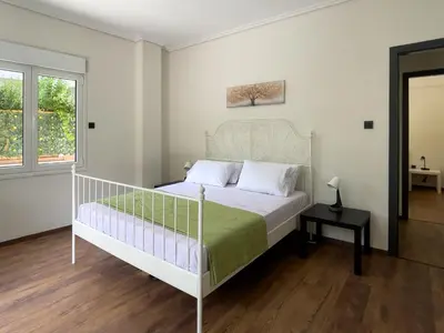 a bedroom with a white bed and a window at Alegria's 2BR Garden Apartment in Athens
