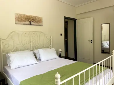 a bedroom with a white bed with a green blanket at Alegria's 2BR Garden Apartment in Athens