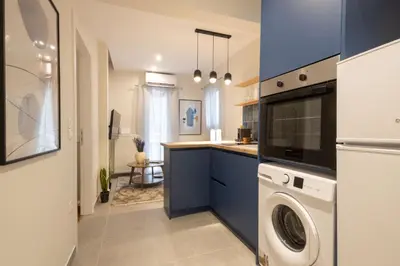 a kitchen with blue cabinets and a washer and dryer at Pagrati Art & Love in Athens