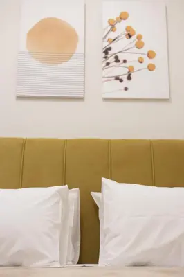 a bed with white pillows and two pictures on the wall at Pagrati Art & Love in Athens