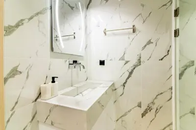 a white bathroom with a sink and a mirror at Cozy 2-Bedroom by Flisvos Marina in Athens