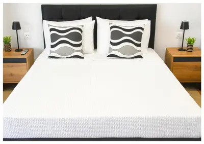 a white bed with black and white pillows at Panathenea Rooftop Apartment with Stunning View of Lycabettus in Athens