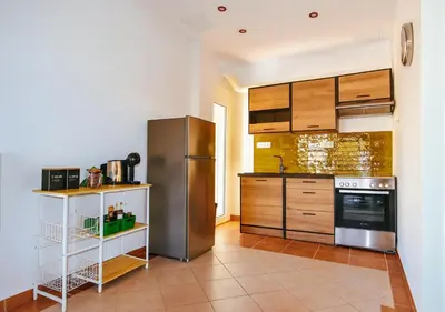 a kitchen with wooden cabinets and a stainless steel refrigerator at Panathenea Rooftop Apartment with Stunning View of Lycabettus in Athens