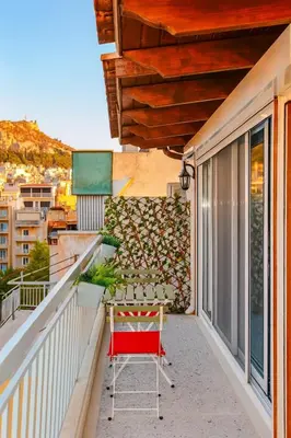 a red chair sitting on the balcony of a building at Panathenea Rooftop Apartment with Stunning View of Lycabettus in Athens