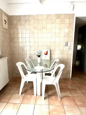 a glass table with white chairs and a vase on it at Shoni home in Piraeus