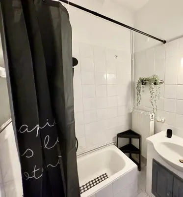 a bathroom with a shower curtain and a tub and a sink at Shoni home in Piraeus