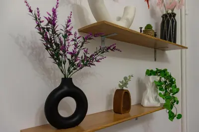 a black vase with purple flowers on a shelf at Mountain Haven - Japandi Style With 100Mbps Wi-Fi in Athens