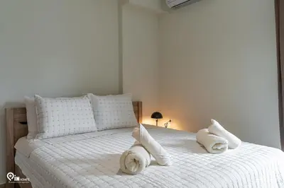 a white bed with white pillows and towels on it at Rubies - Premium And Comfy Stay in Egaleo-Athens in Athens