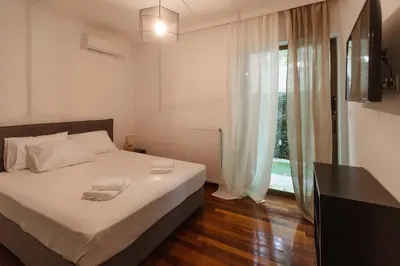 a bedroom with a bed with white sheets and a window at The Hidden Muse 3BD Free Parking in Athens