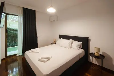 a bedroom with a bed with white sheets and a window at The Hidden Muse 3BD Free Parking in Athens