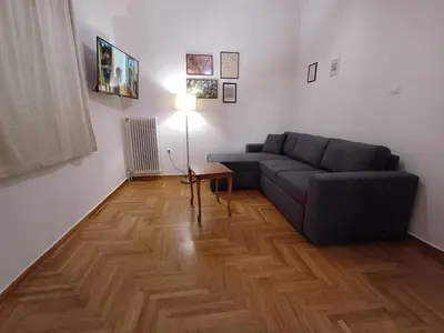 a living room with a couch and a wooden floor at Harmony Athens city apartment in Athens