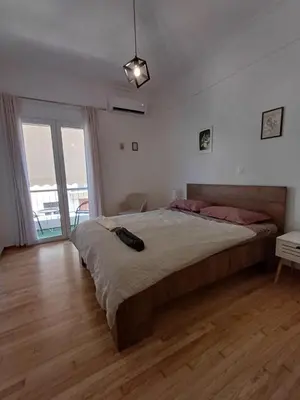 a bedroom with a large bed and a wooden floor at Harmony Athens city apartment in Athens