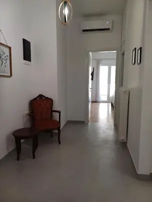 a living room with a chair and a hallway at Harmony Athens city apartment in Athens