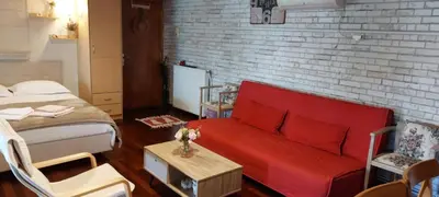 a living room with a red couch and a bed at Rooftop bliss in Athens
