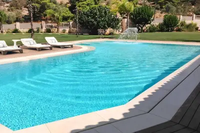 a swimming pool with chairs and a fountain at GT Dreams Villa - Luxury Villa near the Athenian Riviera in Vari