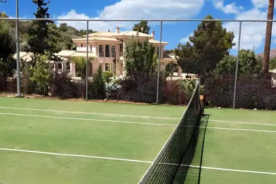 a tennis net on a tennis court in front of a house at GT Dreams Villa - Luxury Villa near the Athenian Riviera in Vari