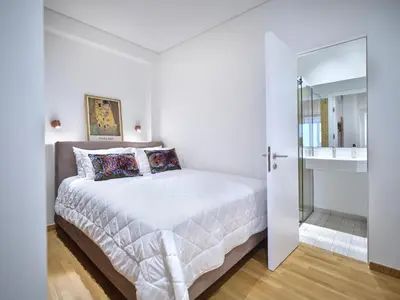 a white bedroom with a bed and a mirror at 30one Kolonaki Apartment in Athens