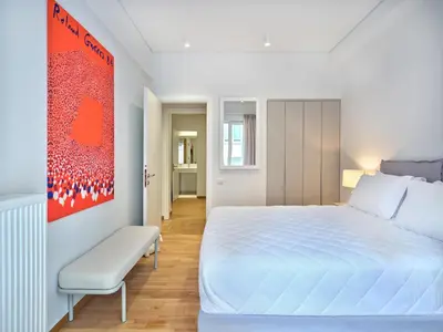 a white bedroom with a white bed and a chair at 30one Kolonaki Apartment in Athens