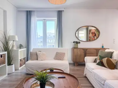 a living room with a white couch and a table at Boho Flat in Glyfada Center in Athens