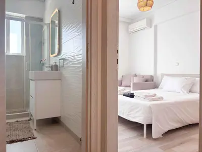 a bedroom with a bed and a bathroom with a sink at Boho Flat in Glyfada Center in Athens