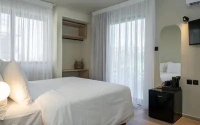 a bedroom with a white bed and a large window at Gnamma Hotel in Athens