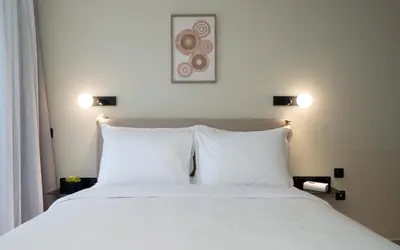 a bed with white pillows in a room at Gnamma Hotel in Athens