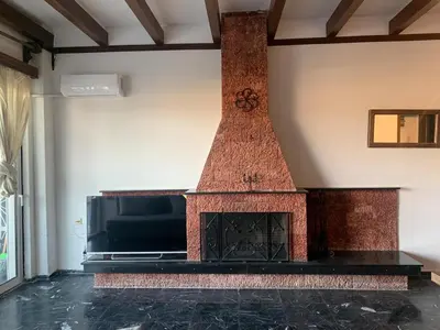 a brick fireplace in a room with a tv at Traditional Apartment in Varkiza in Vari